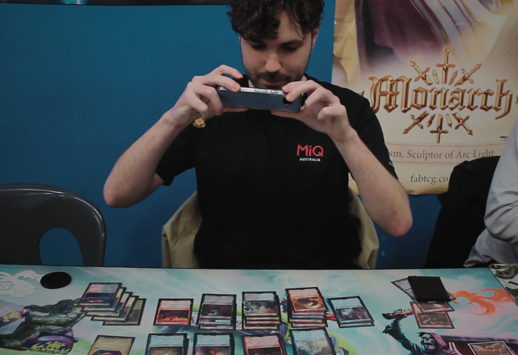 Player taking a photo of cards spread across a playmat